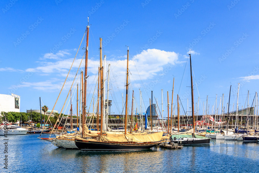 Sailing boats and yachts docked in Port Vell Marina in Barcelona, Catalonia, Spain. Waterfront harbor, famous touristic place at sunny day.