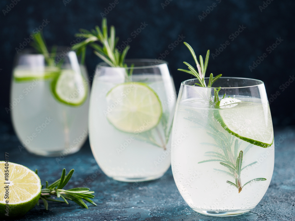 Glasses of alcoholic coctail with fresh rosemary and lime on blue background. Glasses of alcoholic coctail with fresh rosemary and lime on blue background.
