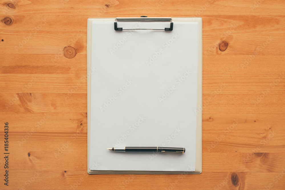 Overhead view of blank clipboard note pad paper with pen Overhead view of blank clipboard note pad paper with pen