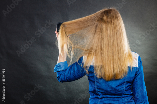 Blonde woman combing her hair.