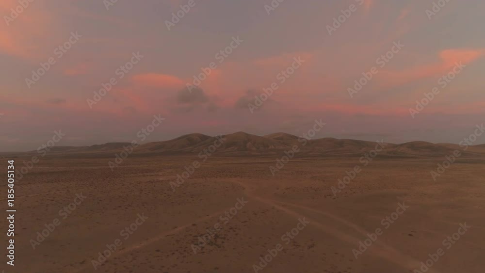 AERIAL: Beautiful summer sunset in lonely volcanic landscape in the Canaries. Dirt roads winding through vast volcanic desert. No people walking or driving through drought-struck landscape at sunset. AERIAL: Beautiful summer sunset in lonely volcanic landscape in the Canaries. Dirt roads winding through vast volcanic desert. No people walking or driving through drought-struck landscape at sunset.