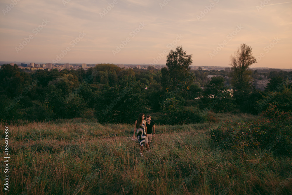 Young couple in love outdoor. Beautiful nature and warm sunset 