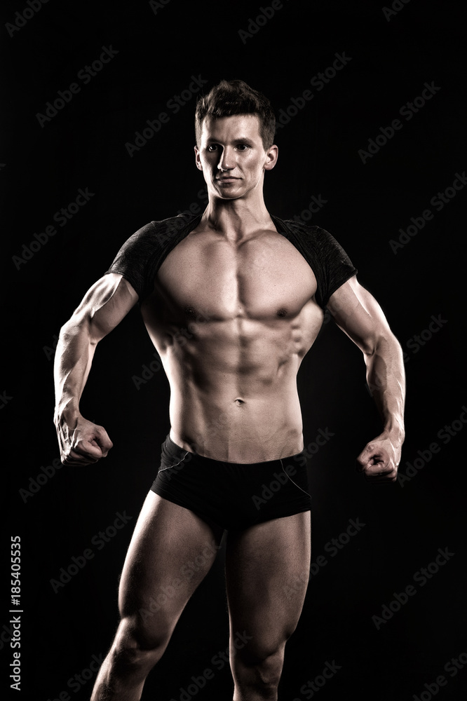 Bodybuilder show muscular body on dark background Bodybuilder show muscular body on dark background