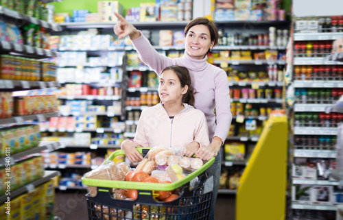 Glad woman and daughter with shopping cart