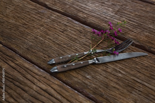 Fork and butter knife with flower on wooden table