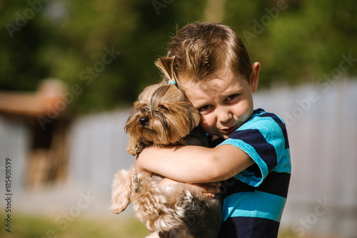 Portrait of a boy with Yorkshire Terrier dog on a walk. Kids pet friendship
