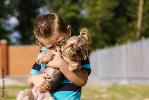 Portrait of a boy with Yorkshire Terrier dog on a walk. Kids pet friendship