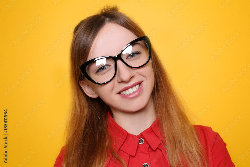 Young attractive woman with eyeglasses on color background