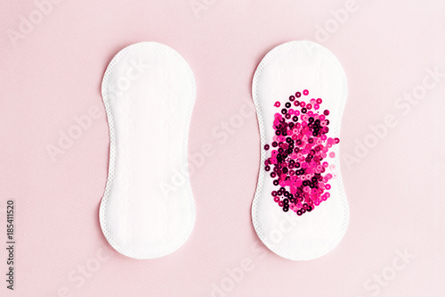 Two menstrual pads with red glitter on pastel pink colored background. Minimalist still life photography concept photo