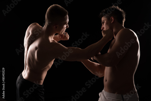 Two fighters facing each other on black background © Geza
