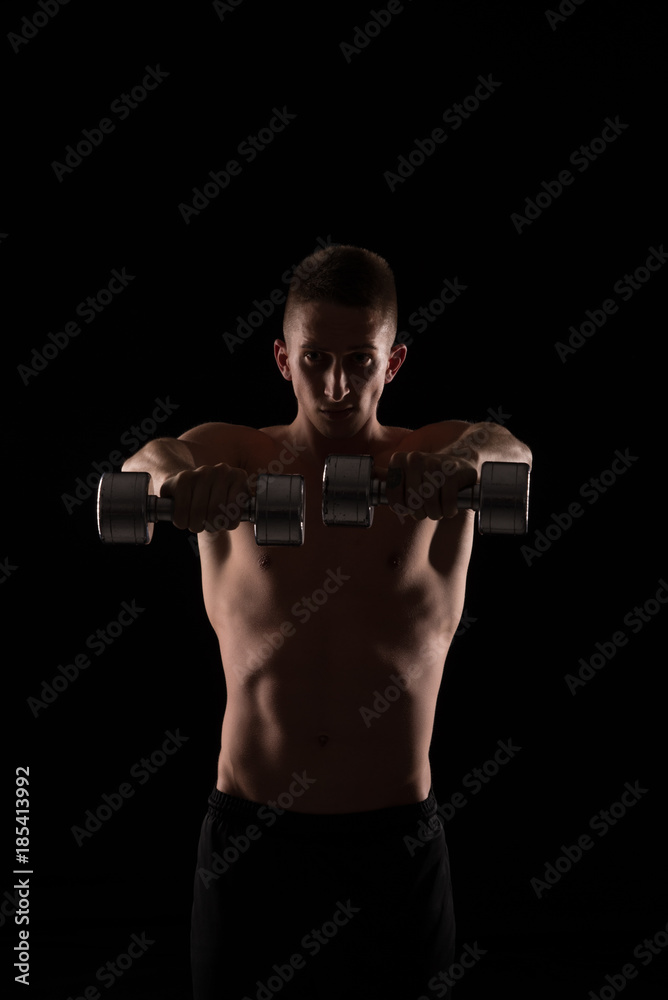 Young athlete exercise with hand weights on black background