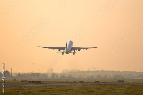 Fotografi airplane taking off on sunset above the runway /plane fly up at sunset yellow sk