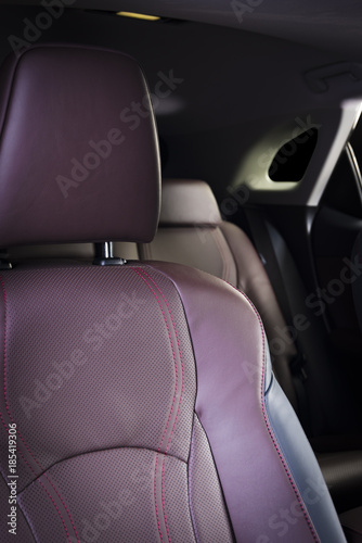 Red leather passenger seat in modern race car, frontal view, blurred back seats in the background, car interior details