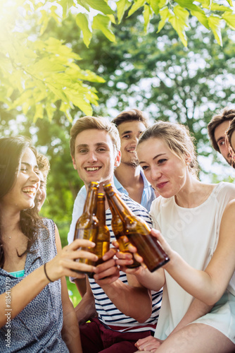 Group of young people having fun, they clink with their beer