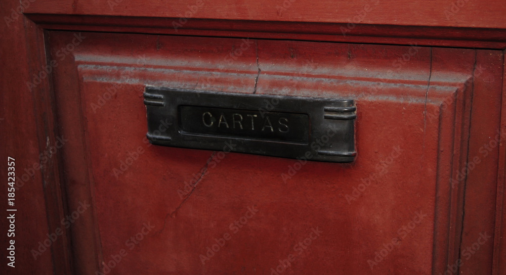Cartas, caixa de correio antiga em metal fixada numa porta de madeira vermelha com inscrições em português Cartas, caixa de correio antiga em metal fixada numa porta de madeira vermelha com inscrições em português