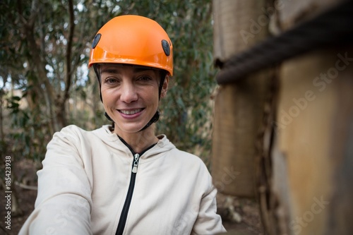 Portrait of woman wearing safety helmet standing in forest