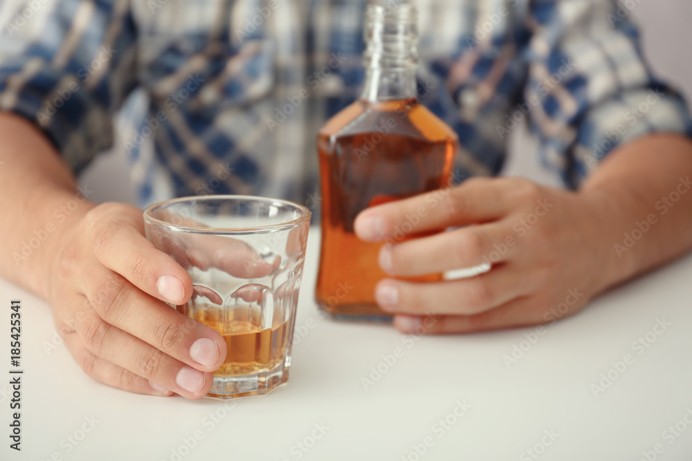 Man with glass and bottle of brandy indoors. Alcohol dependence concept Man with glass and bottle of brandy indoors. Alcohol dependence concept