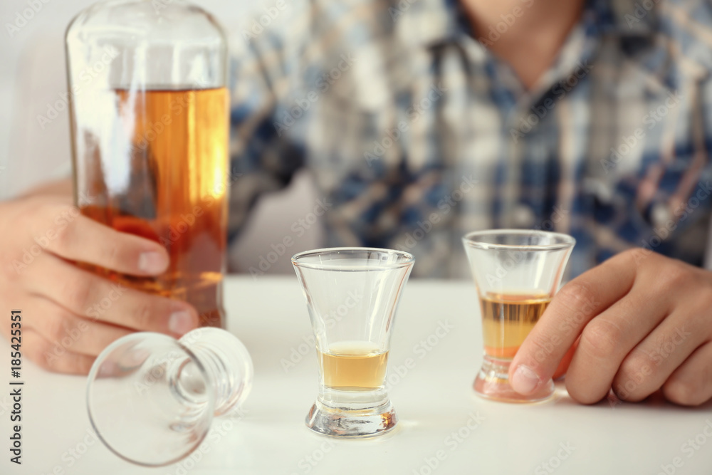 Man with bottle and glasses of brandy indoors. Alcohol dependence concept Man with bottle and glasses of brandy indoors. Alcohol dependence concept
