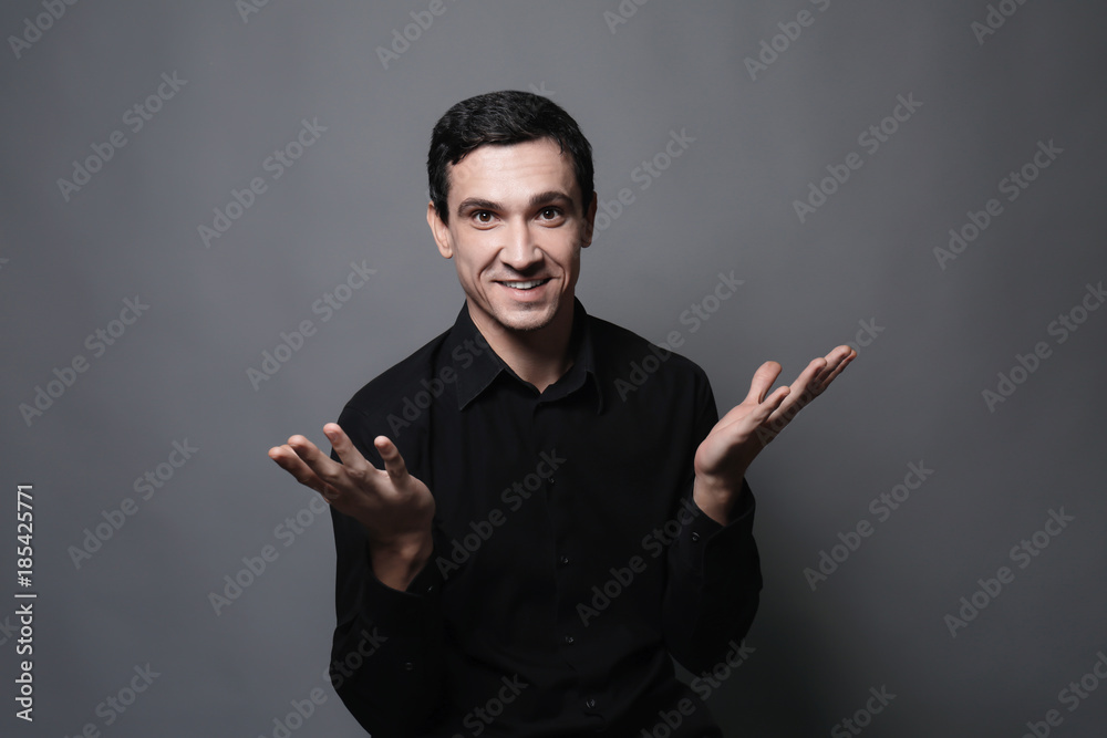 Attractive young man in black shirt on grey background Attractive young man in black shirt on grey background