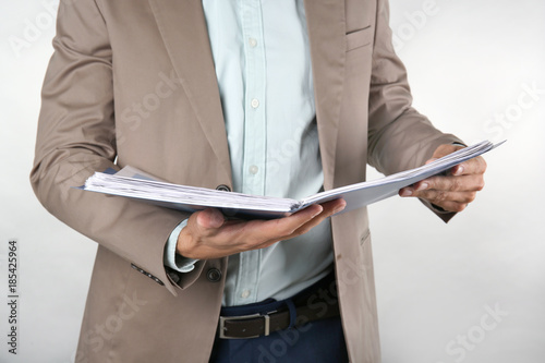 Man holding folder with documents against light background © Africa Studio