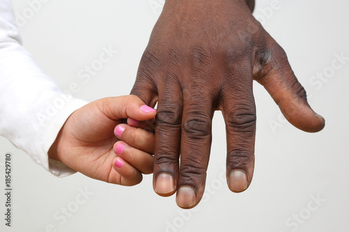 the child holding the hand of a dark-skinned father.