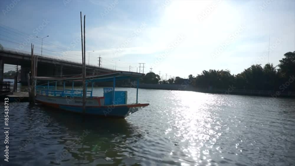 beautiful landscape view of mae klong river,samutsongkram,thailand with bridge and blue sky and cloud against sun while the passenger boat is floating or parking in the evening. beautiful landscape view of mae klong river,samutsongkram,thailand with bridge and blue sky and cloud against sun while the passenger boat is floating or parking in the evening.