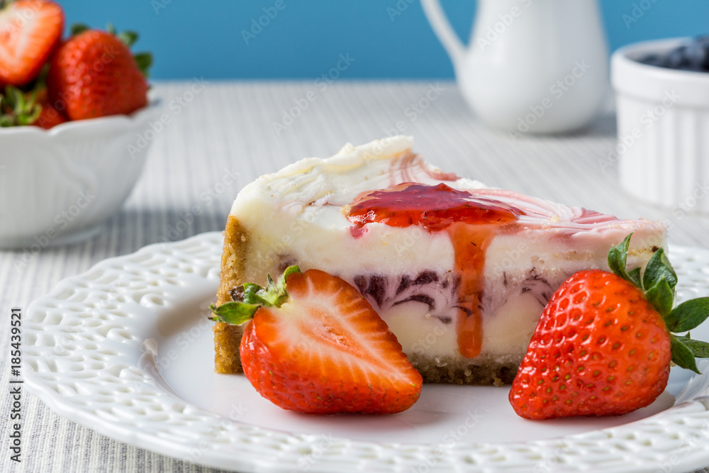 Delicious cheesecake with strawberry on a table against blue wall. Delicious cheesecake with strawberry on a table against blue wall.