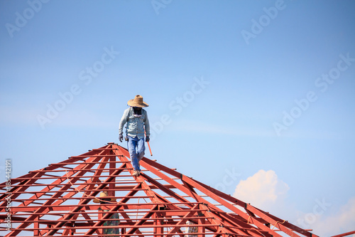 welder workers installing steel frame structure of the house roof at building construction site © Kwangmoozaa