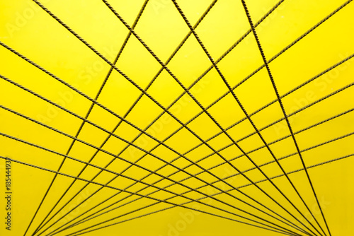 Crossing ropes create an abstract pattern on yellow and white