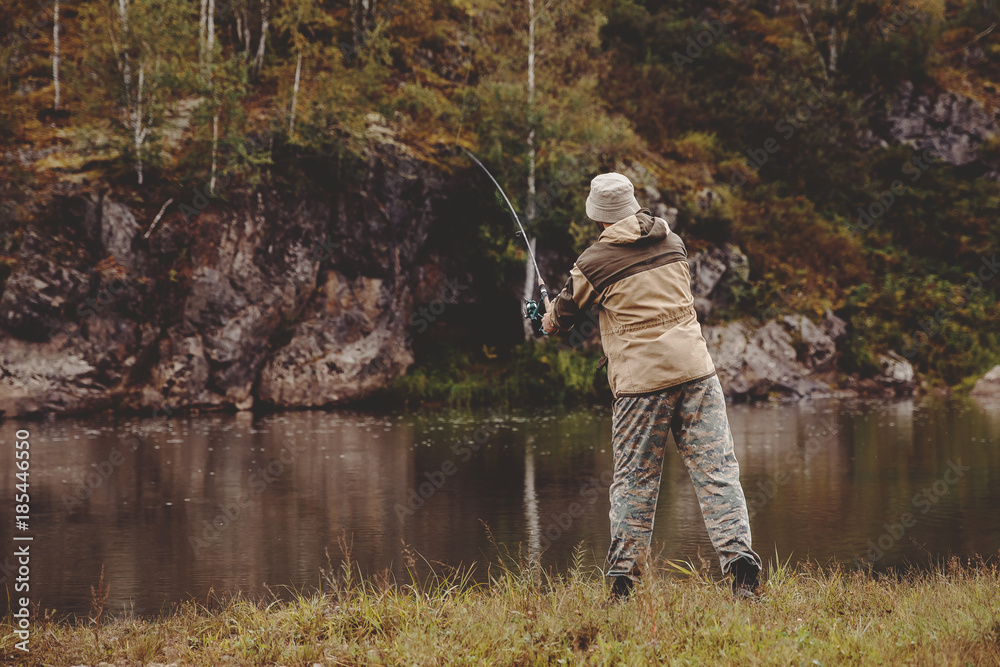 Fishing. The fisherman on a background of rocks throws the fishing rod into the water for catching fish. Concept rest, hobby Fishing. The fisherman on a background of rocks throws the fishing rod into the water for catching fish. Concept rest, hobby