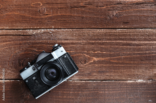 Retro photo camera is lying on a wooden background with a lot of free space on it