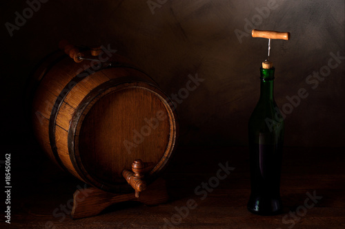  a small wooden wine bar, barrel on the legs and a wooden crane on a wooden background with a glass of wine and bottle of wine