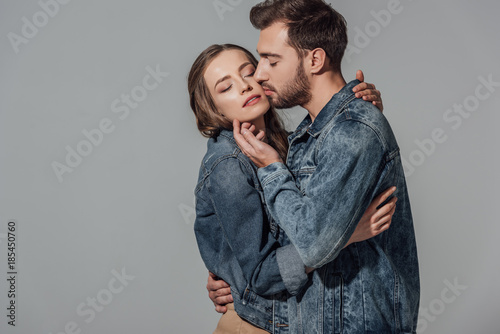 seductive young couple with closed eyes embracing and touching each other isolated on grey