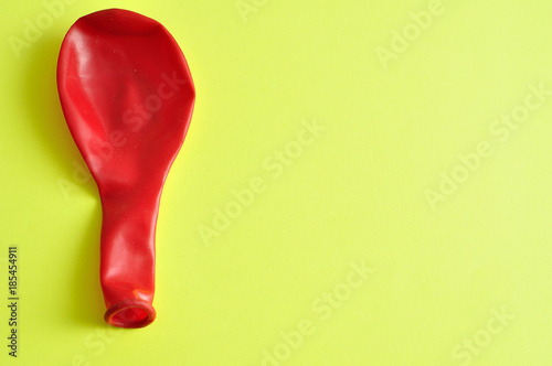 A single red balloon isolated against a yellow background
