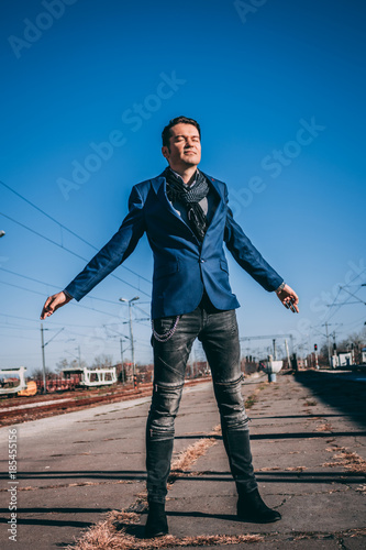 Carefree businessman standing on railway station with arms outstretched.