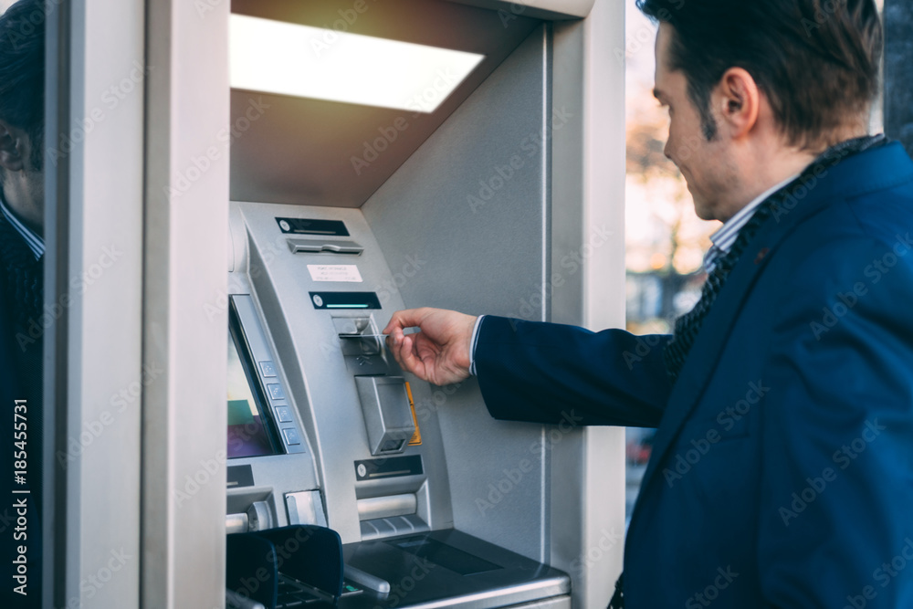Businessman using cash machine and withdrawing money. Businessman using cash machine and withdrawing money.