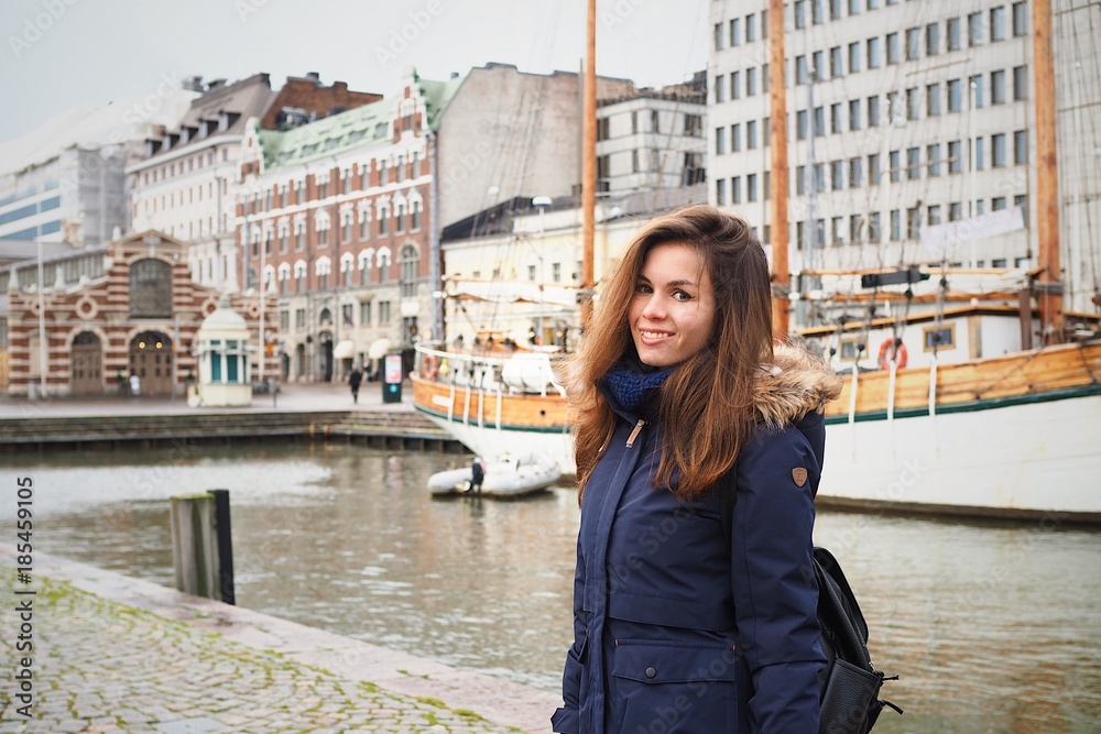 Obraz premium Brunette girl in a winter jacket against the port with yachts
