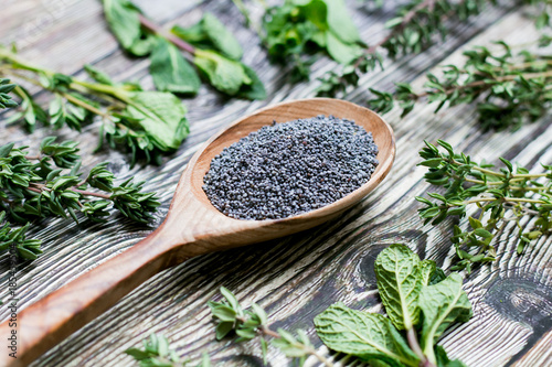 poppy seeds in a wooden spoon on rustic background