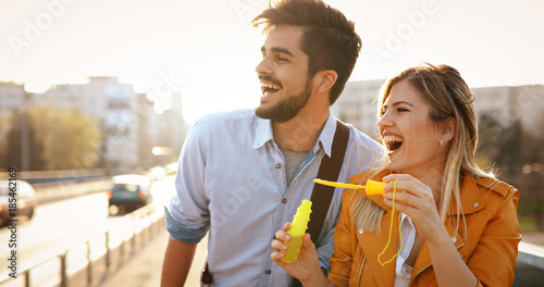 Beautiful young couple blowing soap bubbles and smiling