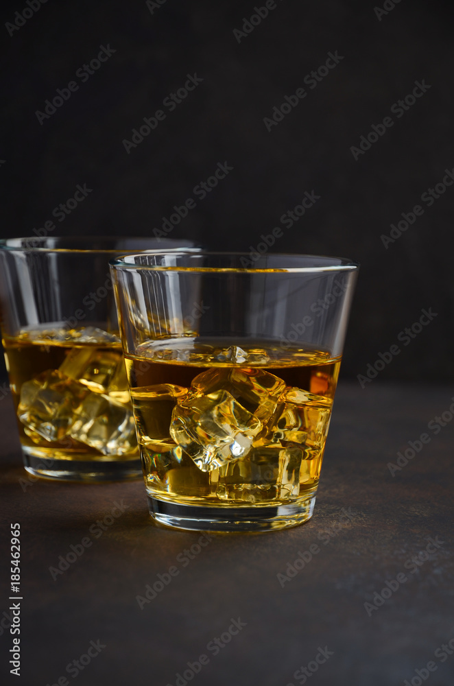 Glass of whiskey with ice on the old rusty background Selective focus Copy space
