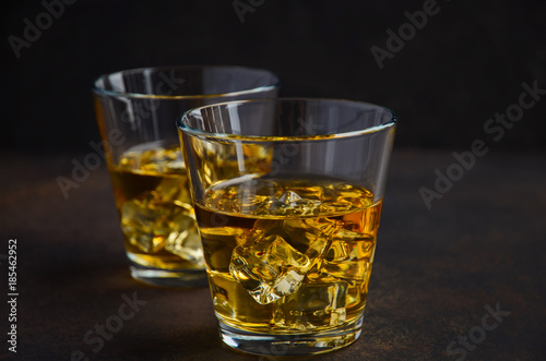 Glass of whiskey with ice on the old rusty background Selective focus