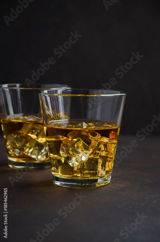 Glass of whiskey with ice on the old rusty background Selective focus Copy space