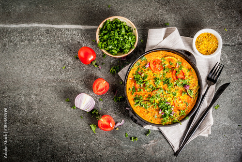 Indian food recipes, Masala Omelette with fresh vegetables - tomato, hot chili pepper, parsley, dark stone background, copy space top view