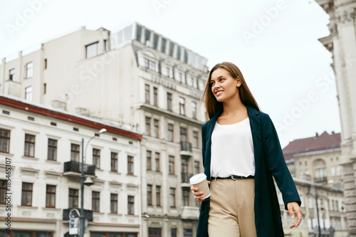 Beautiful Woman With Cup Of Coffee Walking On Street.