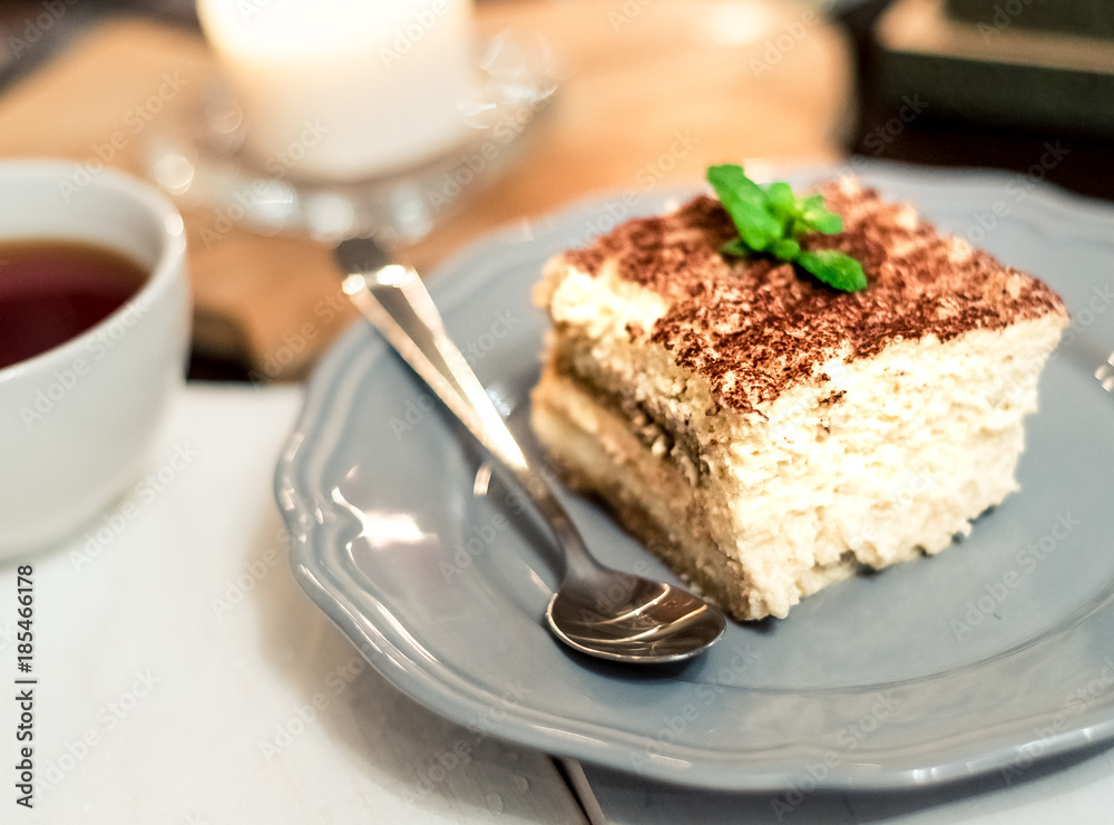 tiramisu by candlelight, romantic date in Italy, tiramisu dessert on a porcelain plate tiramisu by candlelight, romantic date in Italy, tiramisu dessert on a porcelain plate