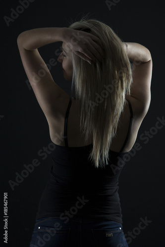 Beautiful blond woman in denim and black top in the dark with selective lighting