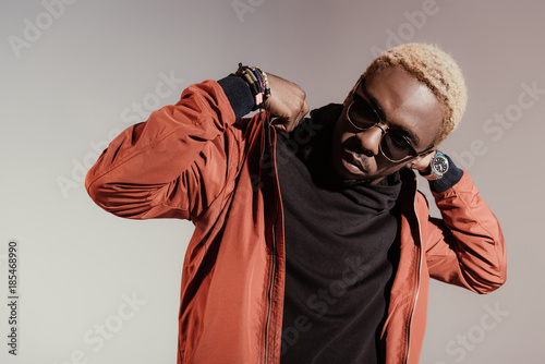 Stylish young african american man straightens his jacket isolated on light background photo