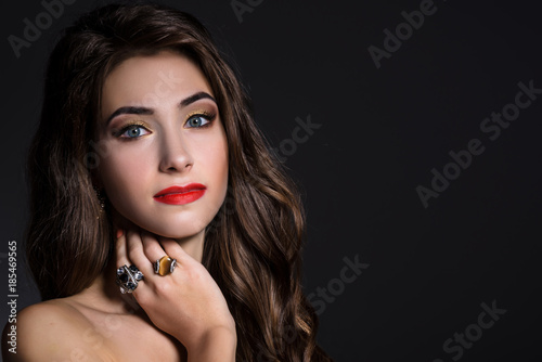 Woman with long curly hair, makeup, red lips and in jewelry