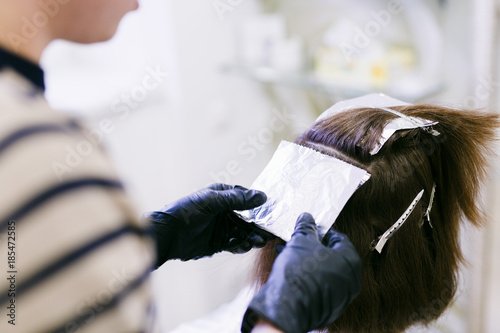 the hairdresser in the beauty salon makes hair coloring