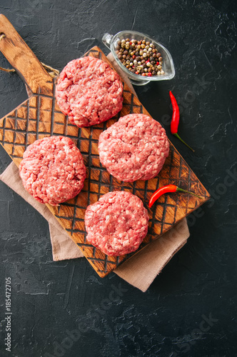 Raw ground meat beef burgers on a wooden board. Top view.